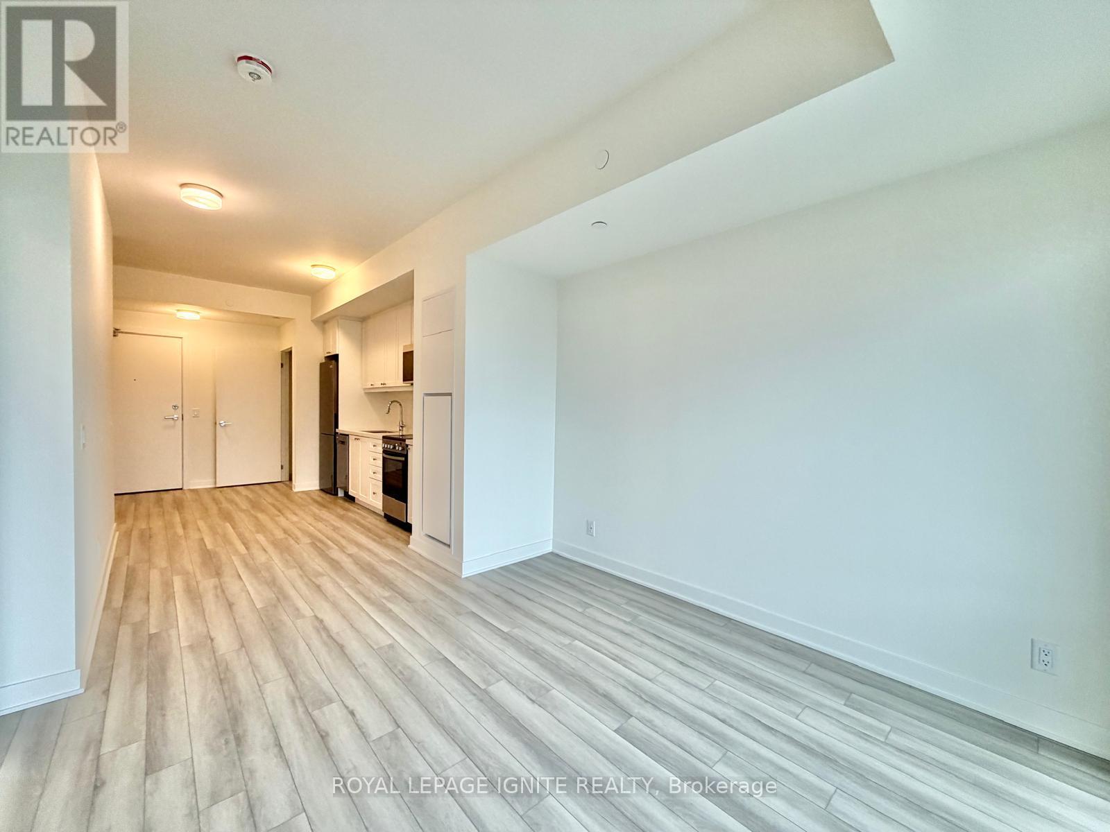 A spacious room with wooden flooring and white walls.