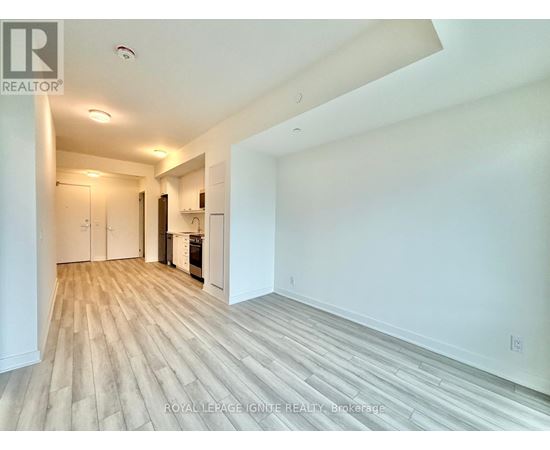 A spacious room with wooden flooring and white walls.