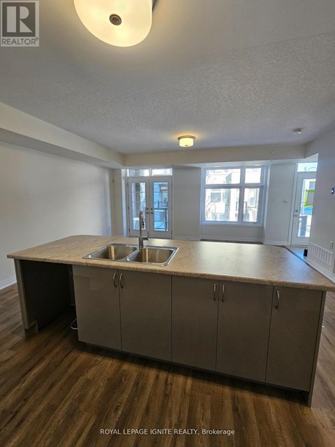 A kitchen with a sink and cabinets in a room with wood floors.