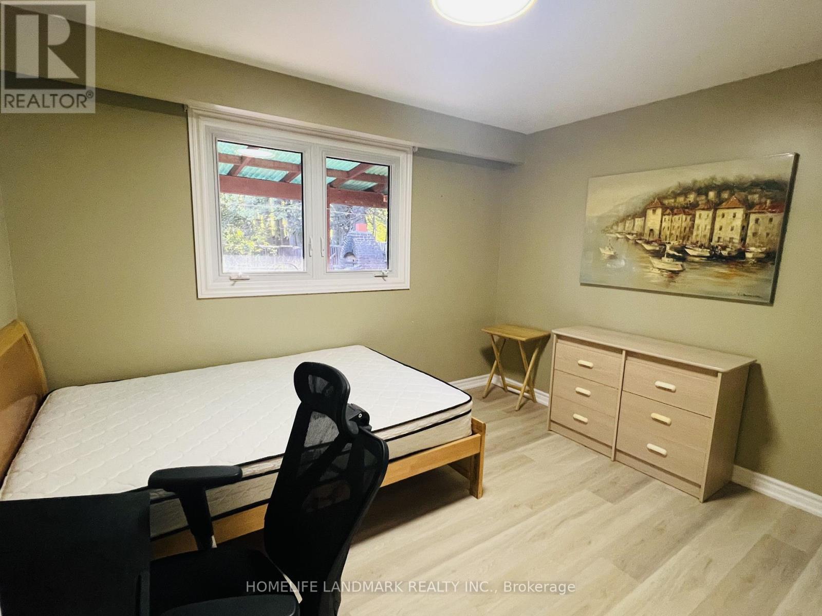 A bedroom with a bed, chair, and a painting on the wall.
