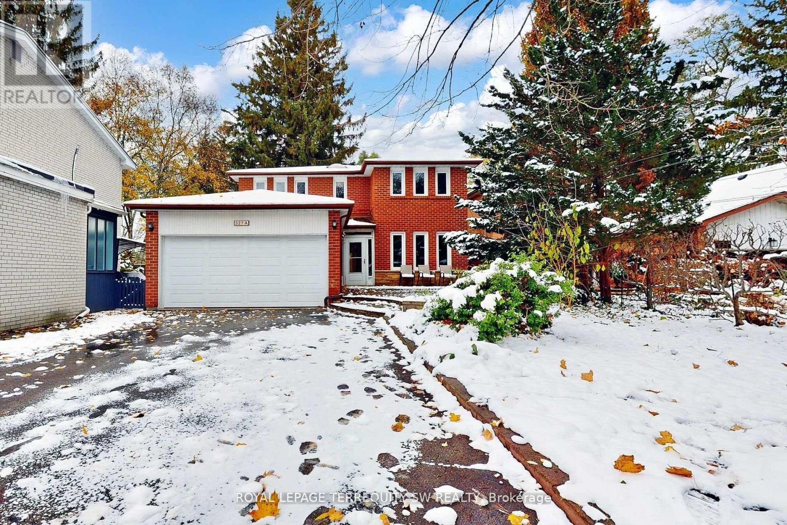 A snow-covered yard with a brick house and a garage.