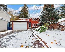 A snow-covered yard with a brick house and a garage.