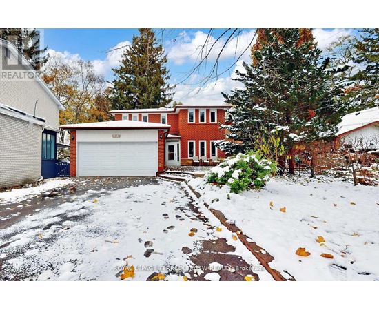 A snow-covered yard with a brick house and a garage.