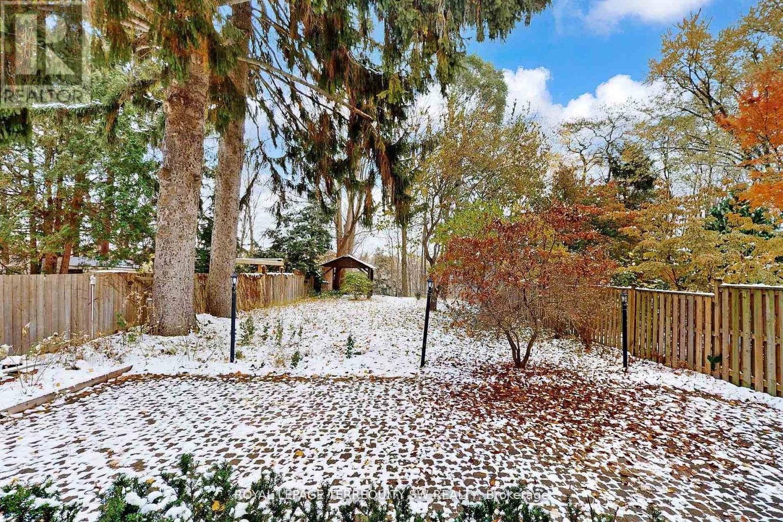 A snowy backyard with a fence and trees.