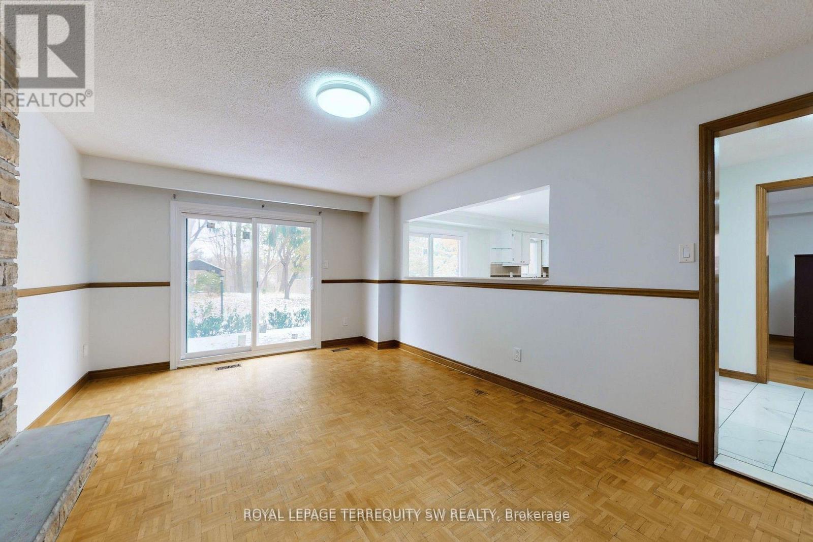 A spacious room with wooden flooring and a sliding glass door leading to a balcony.