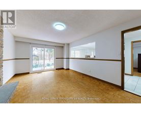 A spacious room with wooden flooring and a sliding glass door leading to a balcony.