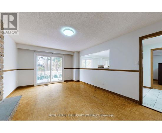 A spacious room with wooden flooring and a sliding glass door leading to a balcony.