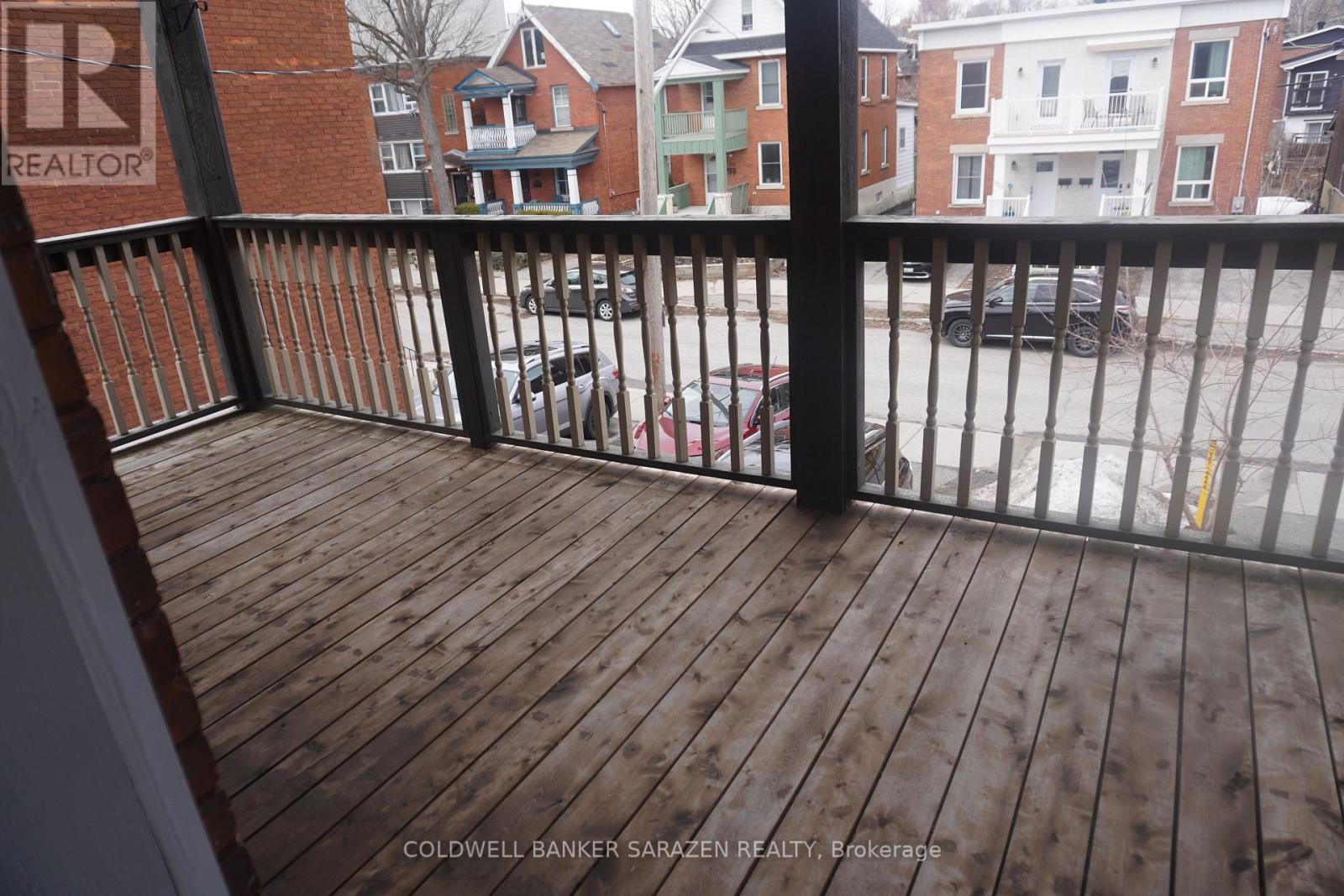 A balcony with a railing and a view of a parking lot and buildings.