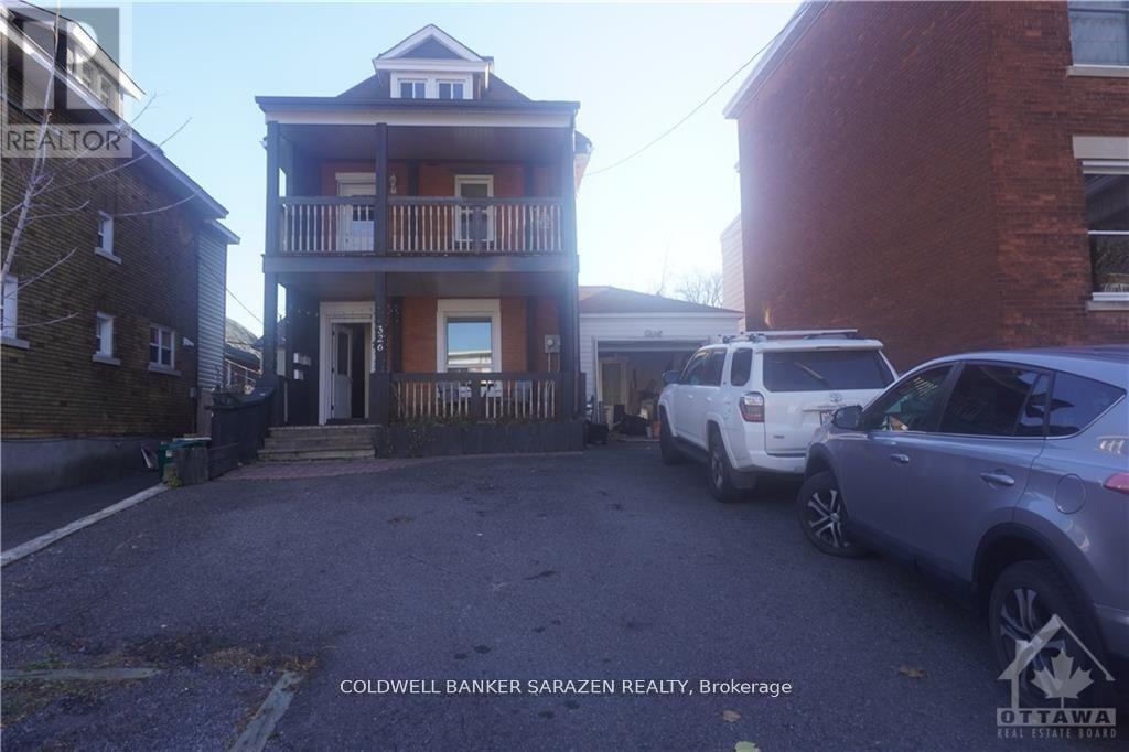 A two-story house with a balcony is shown with a car parked in front.