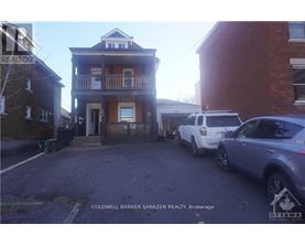 A two-story house with a balcony is shown with a car parked in front.