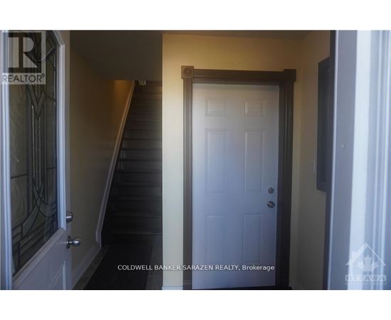 A white door is in a hallway with a staircase.