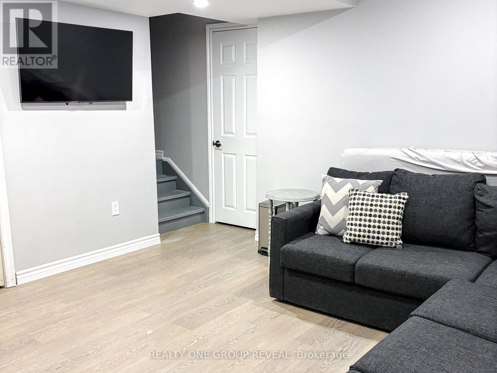 A living room with a grey couch and a flat screen TV mounted on the wall.