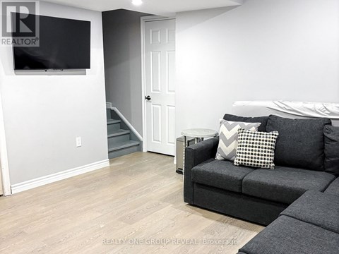A living room with a grey couch and a flat screen TV mounted on the wall.
