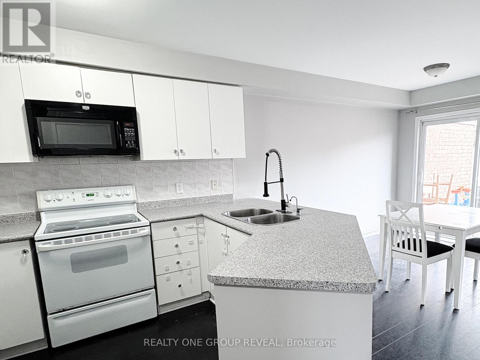 A kitchen with white cabinets and a granite countertop.
