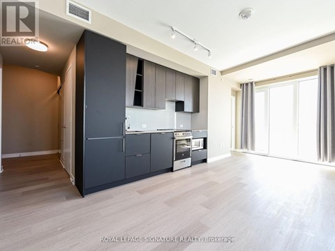 A spacious kitchen with dark grey cabinets and a wooden floor.