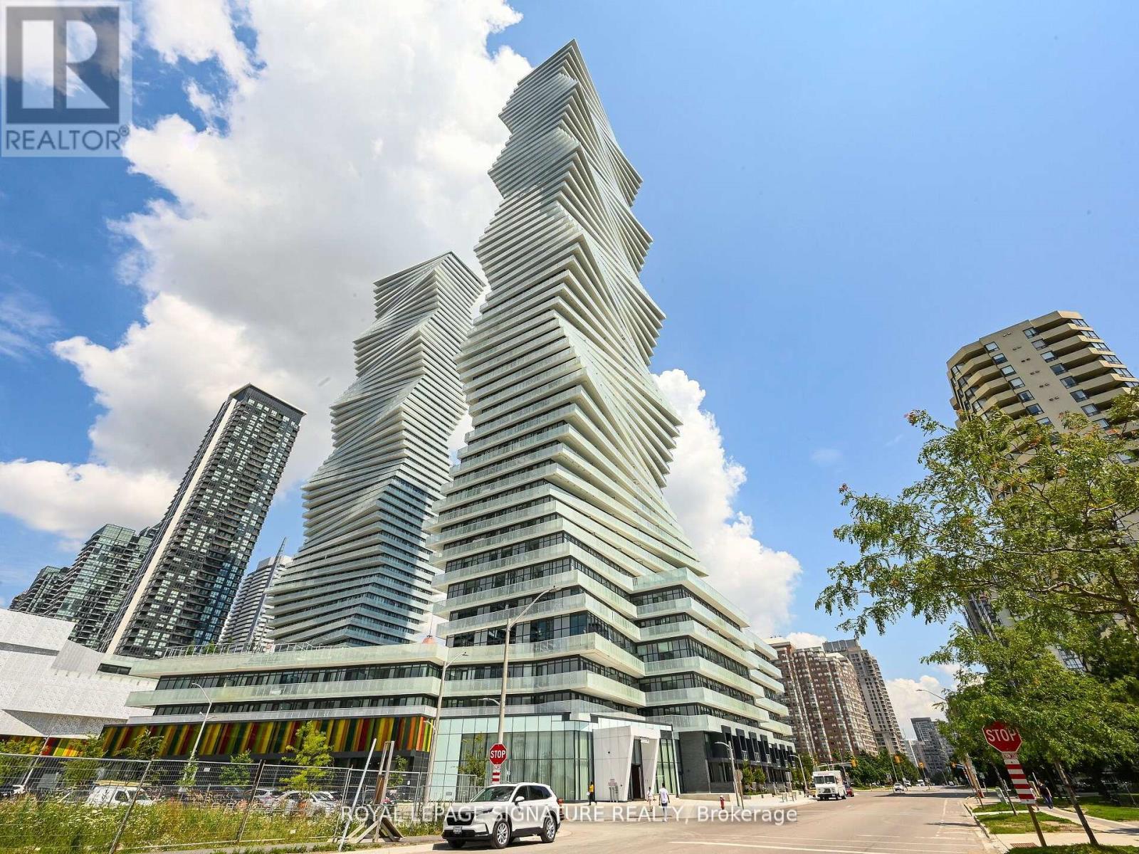 A modern building with a unique curved design stands out in a cityscape.
