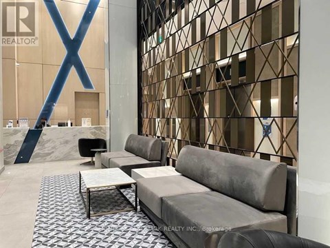 A modern living room with a grey sofa and a glass wall.