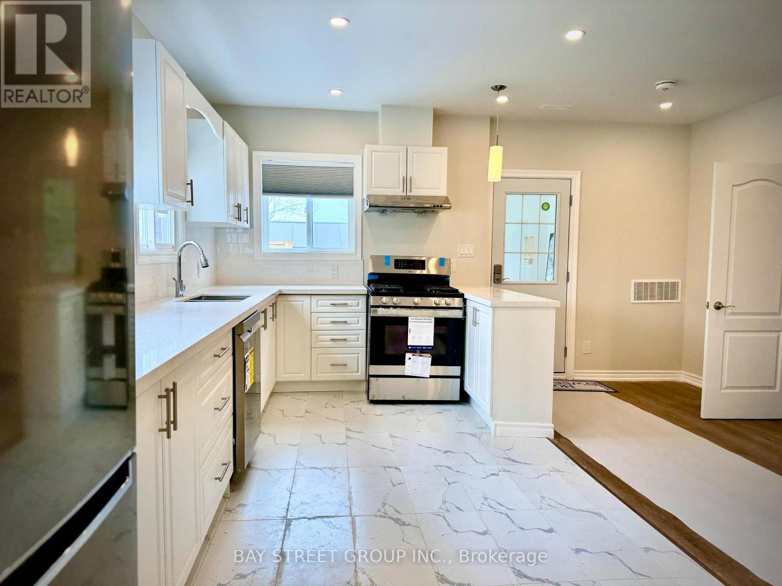A kitchen with white cabinets and a marble floor.
