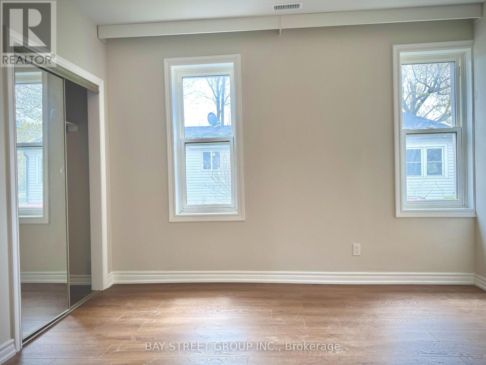 A room with two windows and a door leading to another room.
