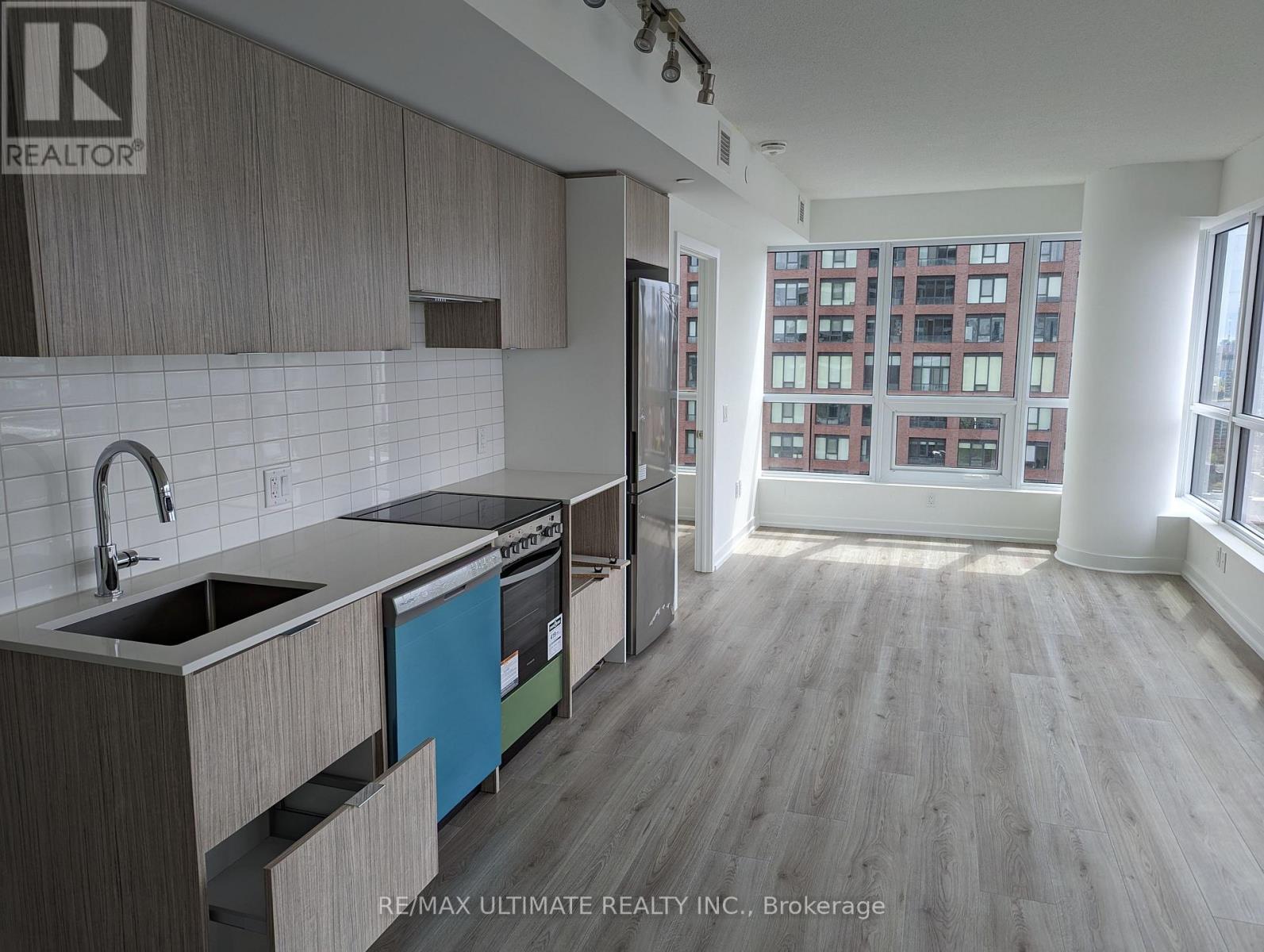 A kitchen with a sink, stove, and refrigerator in a large open space.