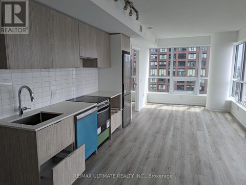 A kitchen with a sink, stove, and refrigerator in a large open space.