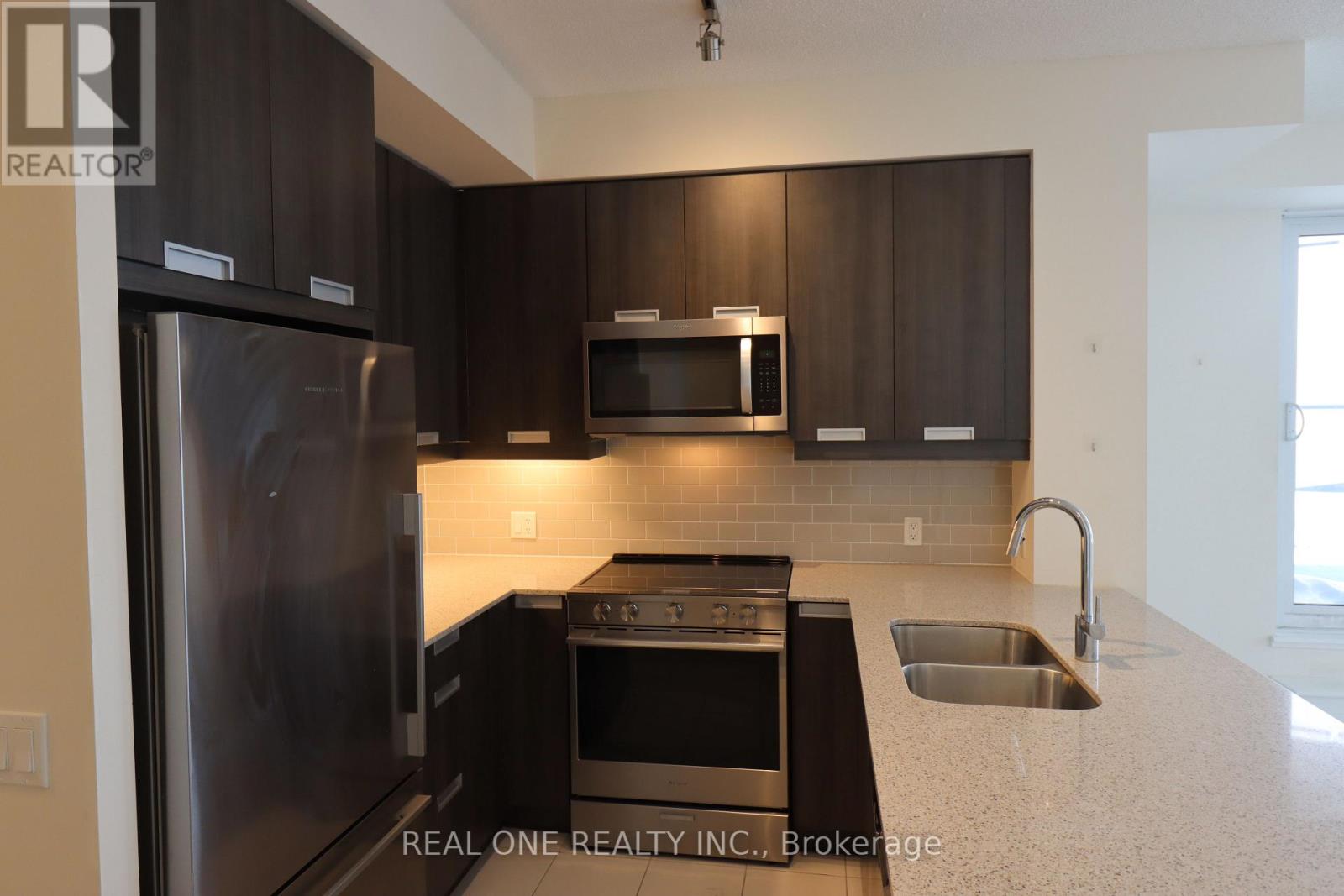 A modern kitchen with dark brown cabinets and stainless steel appliances.