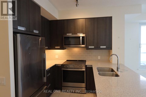 A modern kitchen with dark brown cabinets and stainless steel appliances.