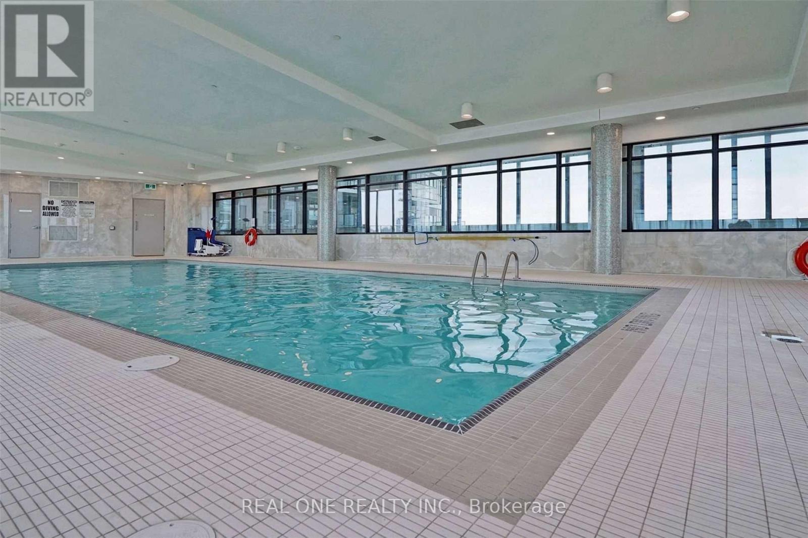 A large indoor swimming pool with a tiled floor and walls.