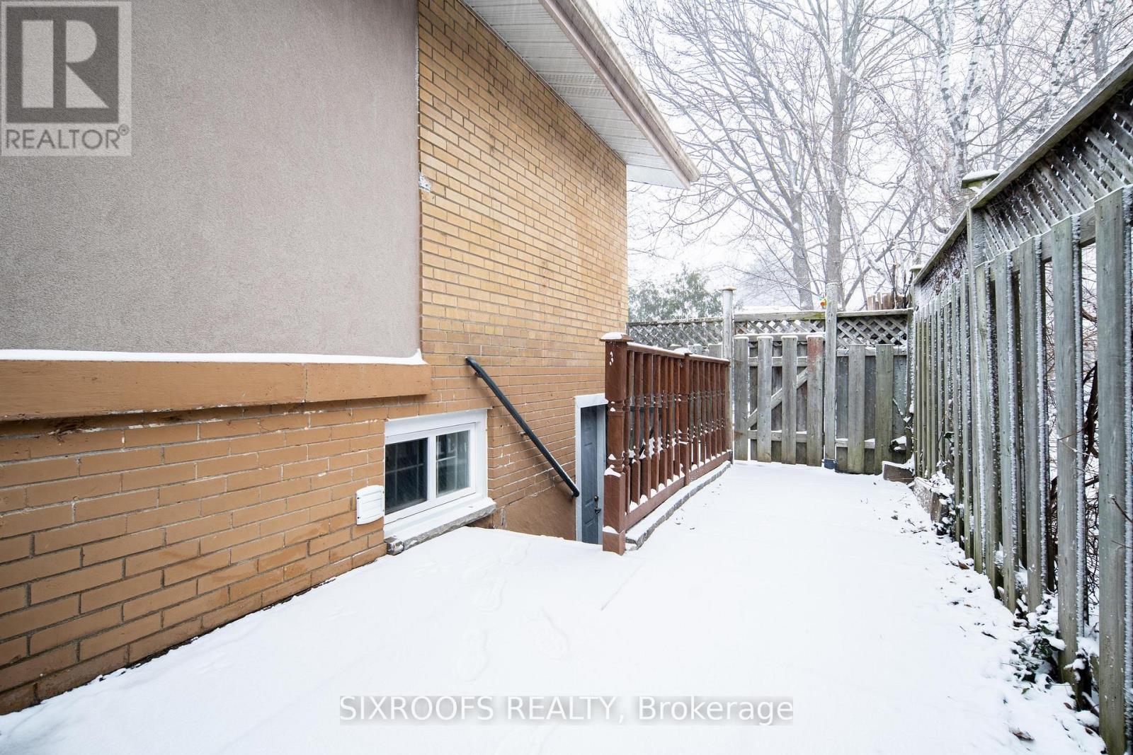 A snow-covered yard with a brick building and a metal fence.