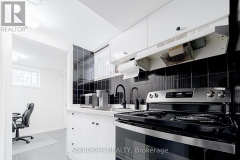 A modern kitchen with a black stove top oven and white cabinets.