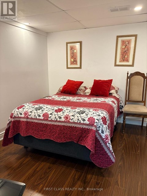 A bedroom with a bed covered in a red and white quilt and two red pillows.