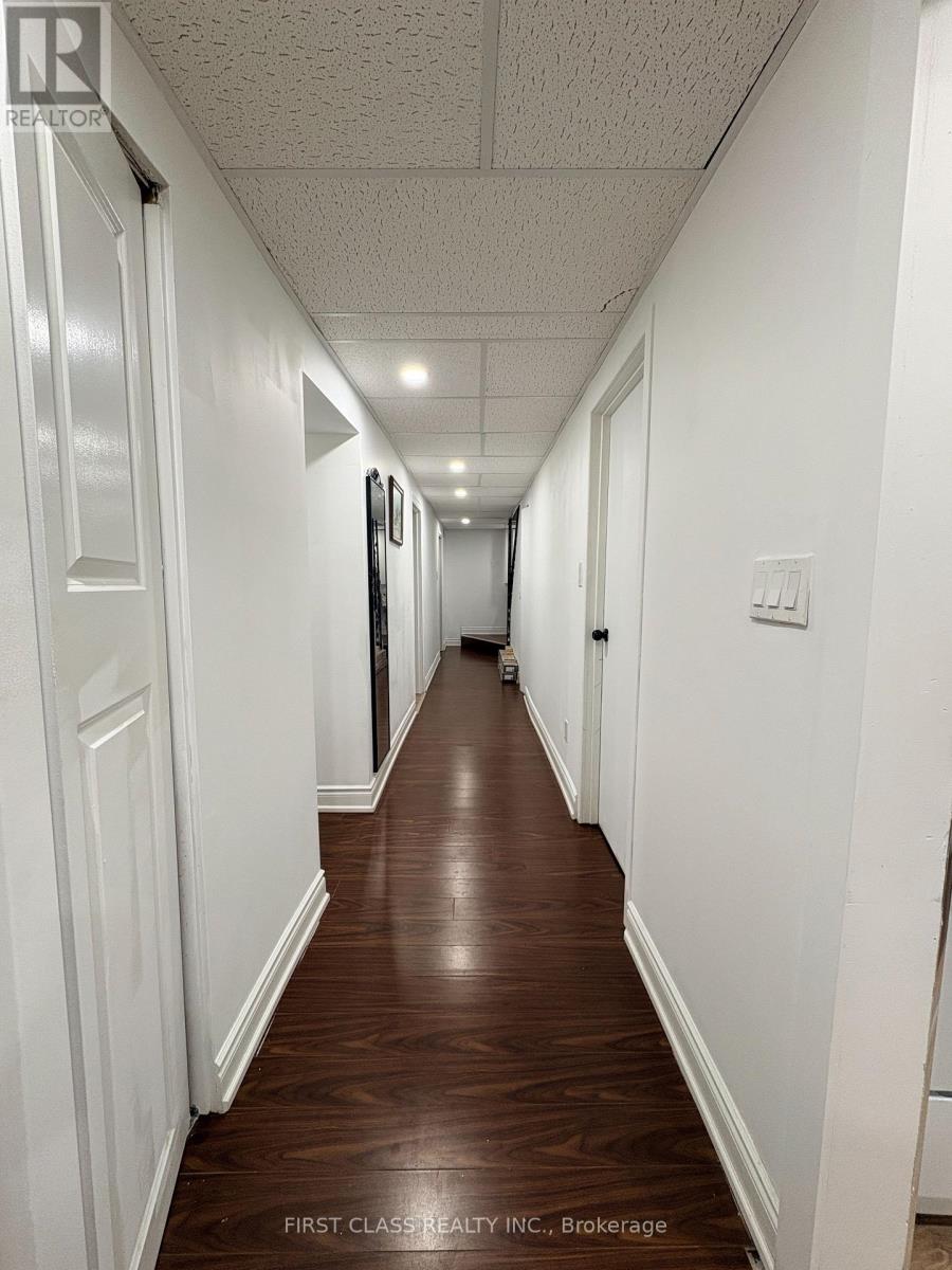 A long hallway with wood floors and white walls.