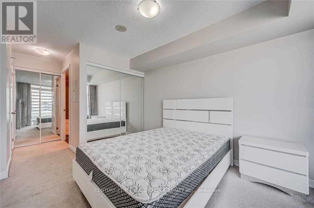 A bedroom with a large bed and a mirrored wall.