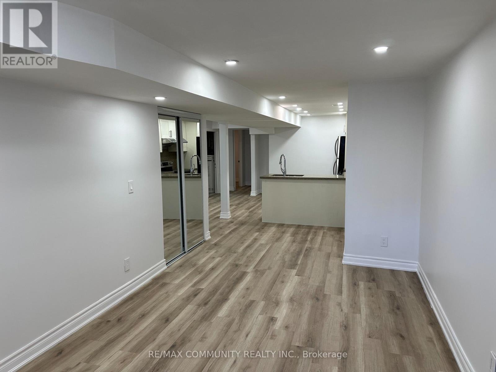 A spacious room with wooden flooring and white walls.