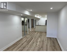 A spacious room with wooden flooring and white walls.