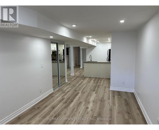 A spacious room with wooden flooring and white walls.