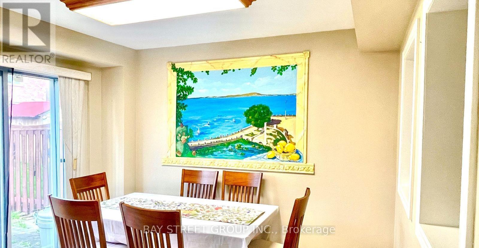 A dining room with a table set for six and a painting of a beach scene on the wall.