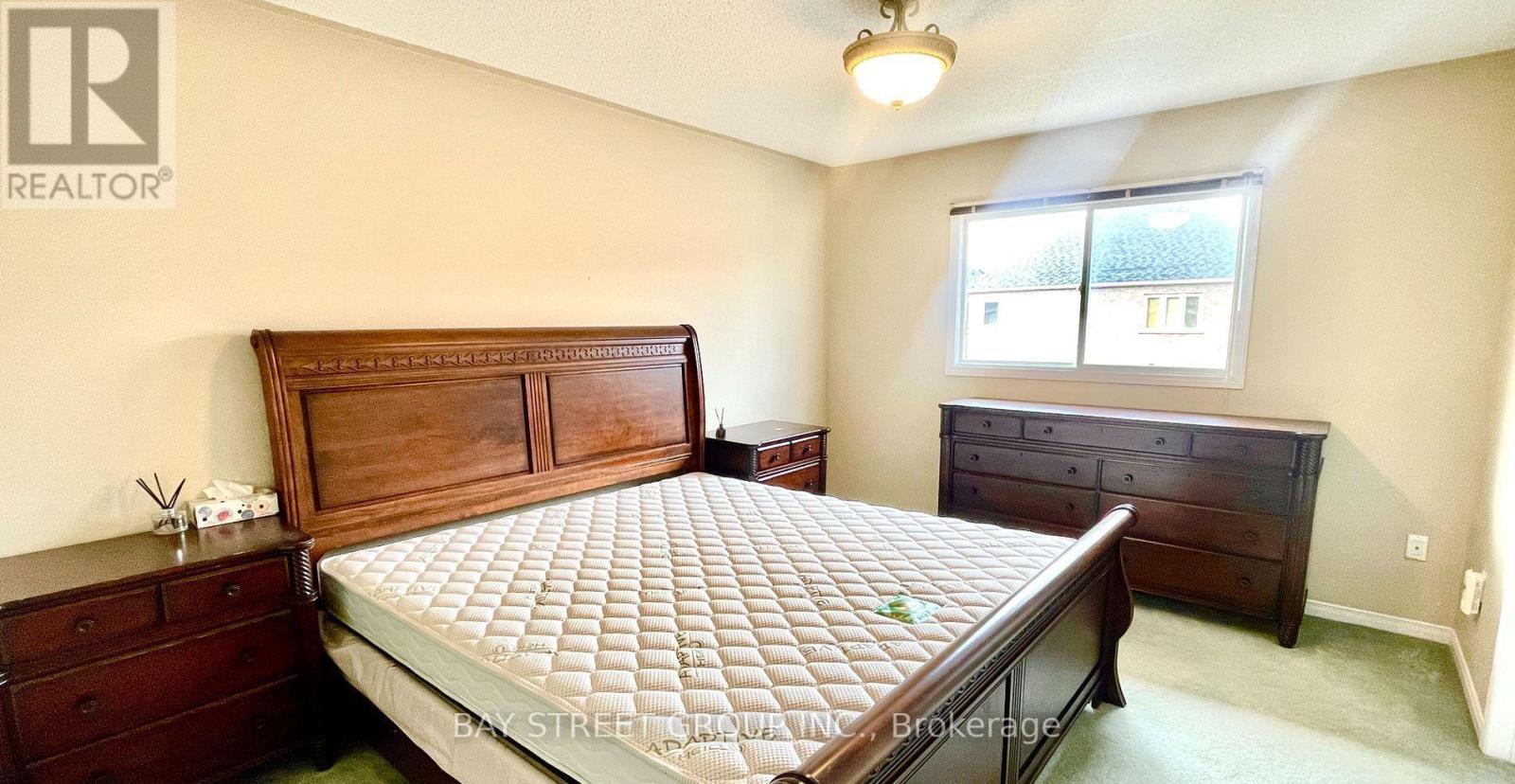 A bedroom with a large bed, a dresser, and a window.