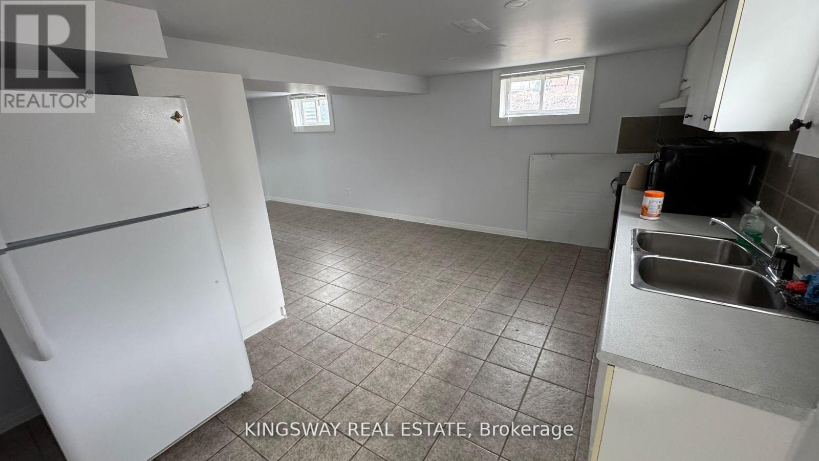 A kitchen with a white fridge and a tiled floor.