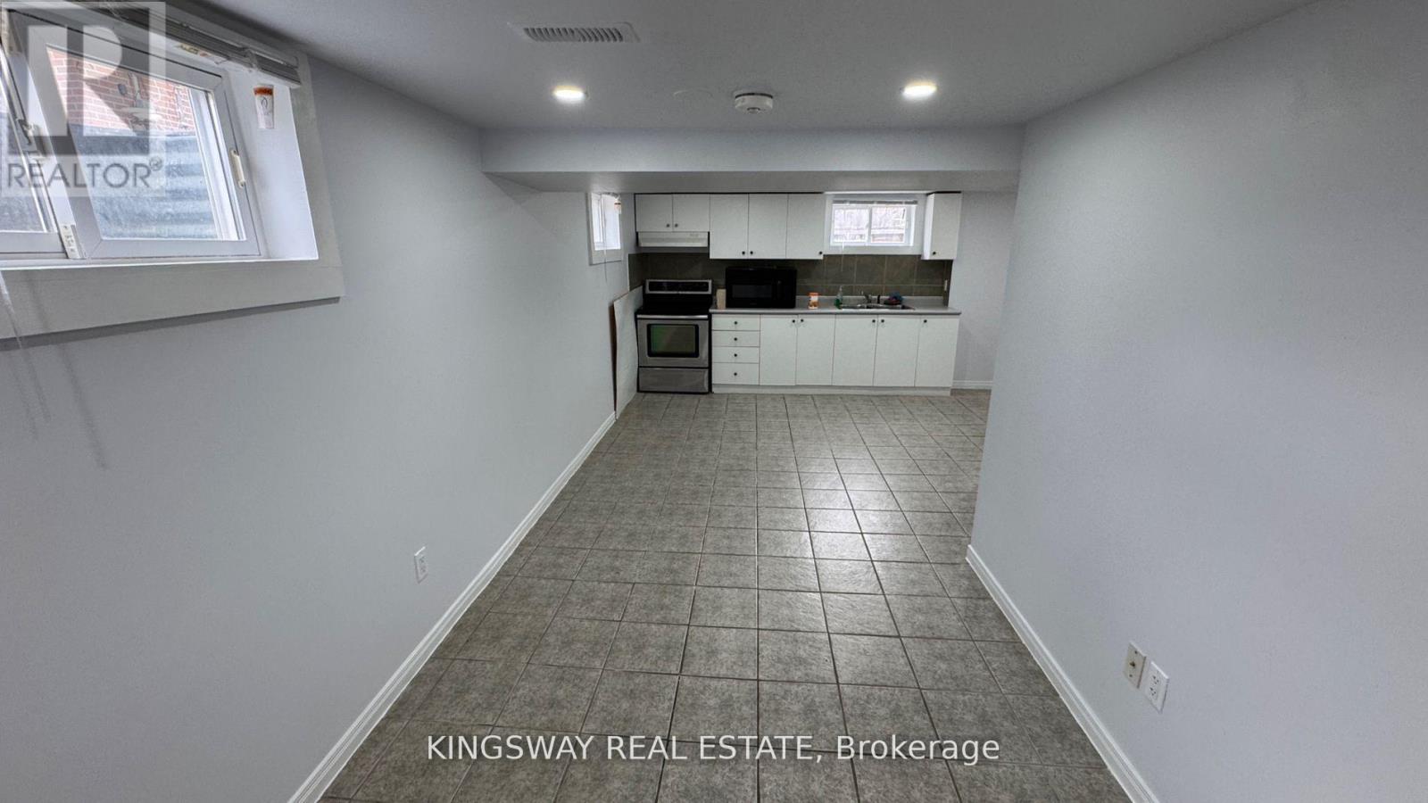 A kitchen area with white cabinets and a tiled floor.