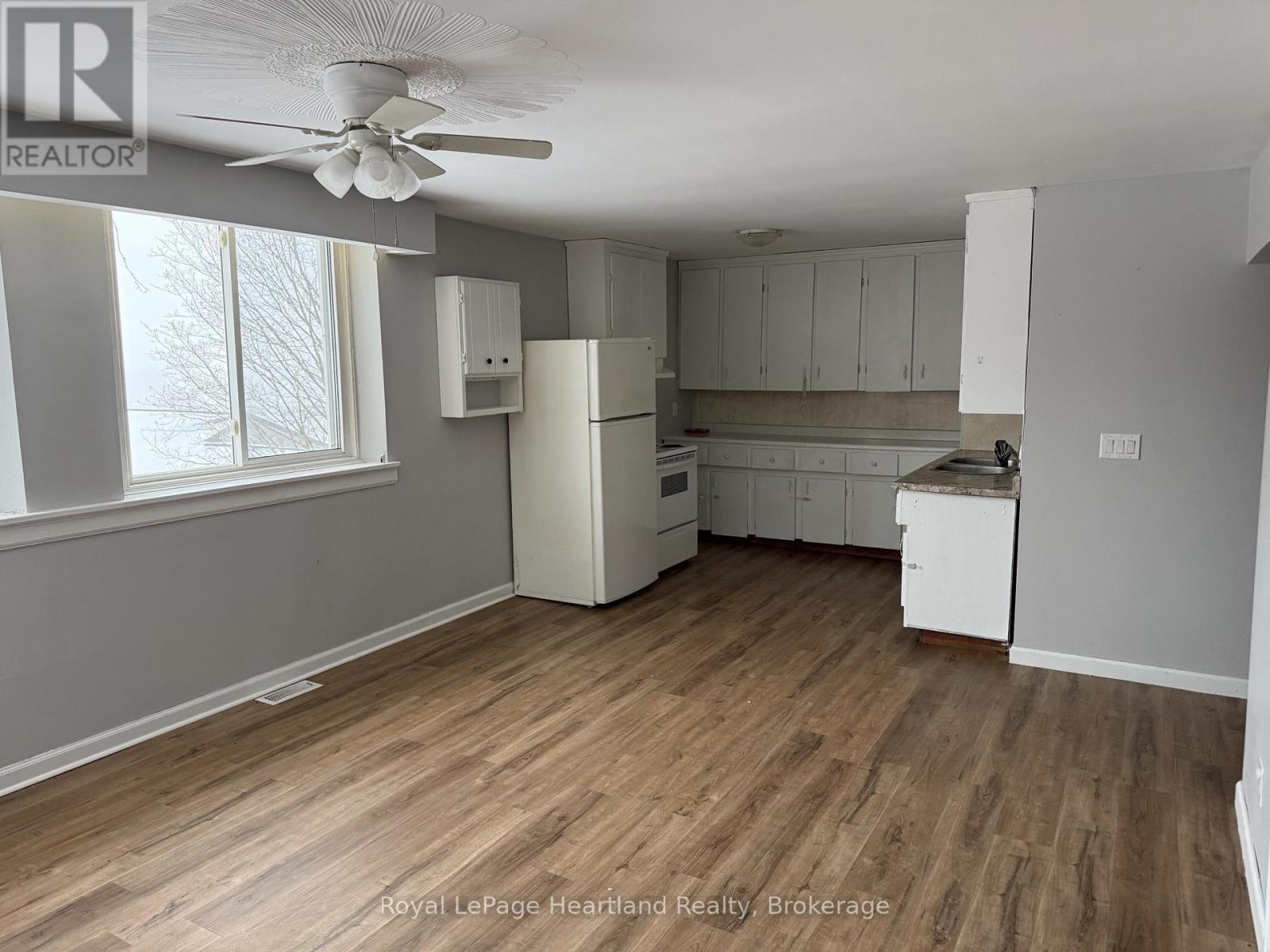 A kitchen with white cabinets and a wooden floor.