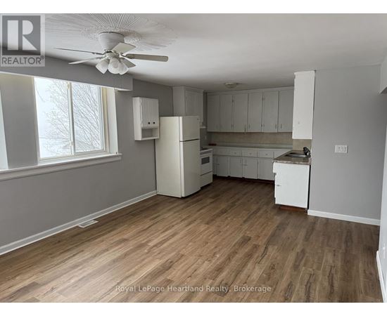 A kitchen with white cabinets and a wooden floor.