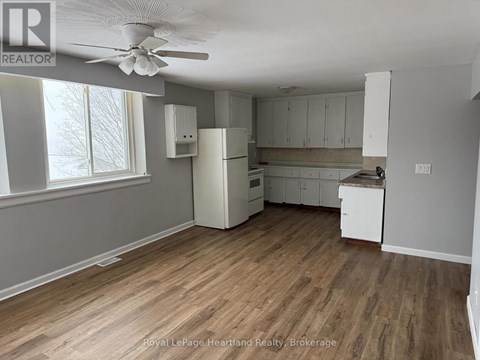 A kitchen with white cabinets and a wooden floor.