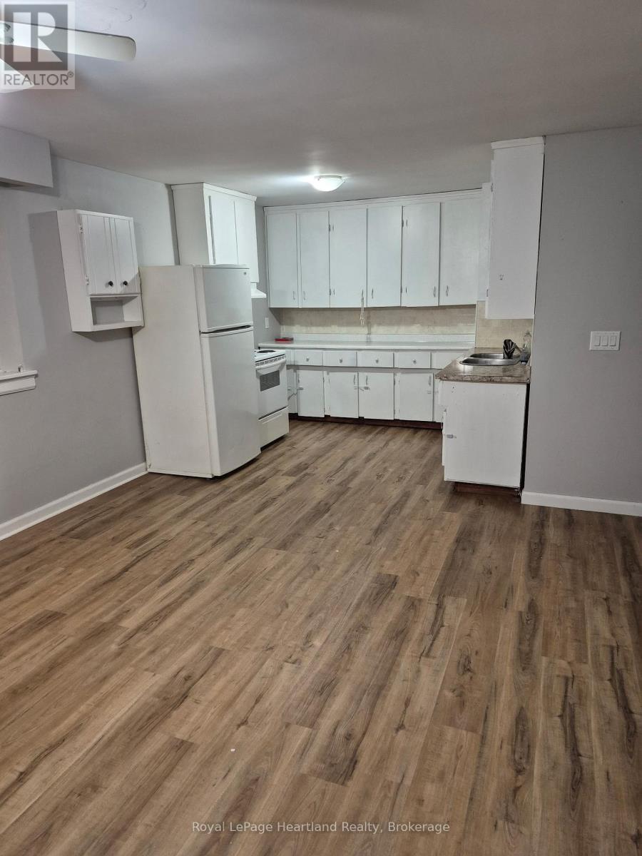 A kitchen with white appliances and wooden floors.