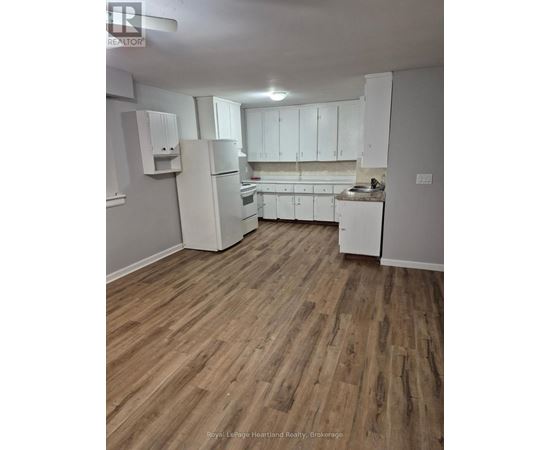 A kitchen with white appliances and wooden floors.