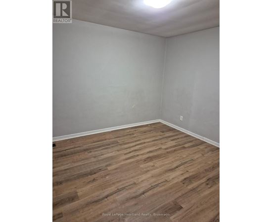 A room with wooden flooring and white walls.