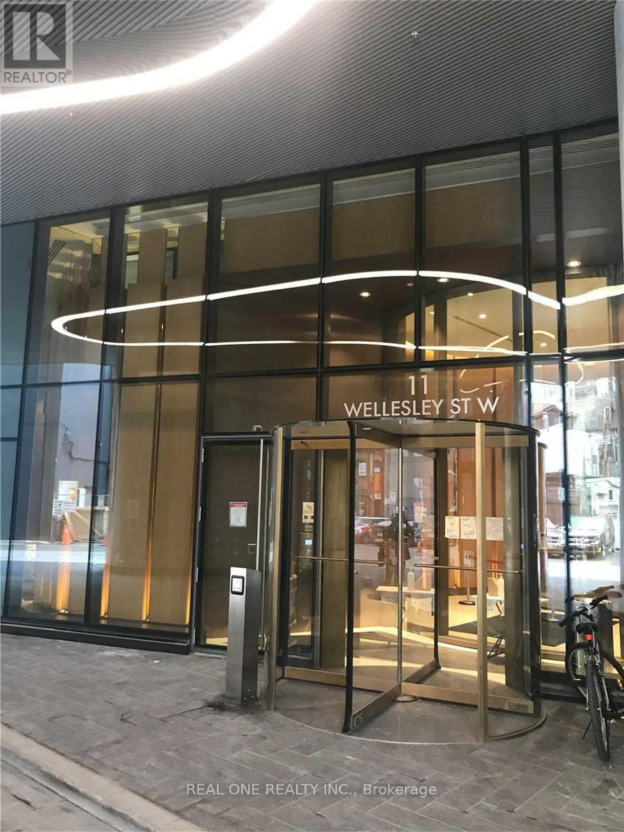 The entrance to a building with a glass door and a sign that reads "11 Wellesley St W".