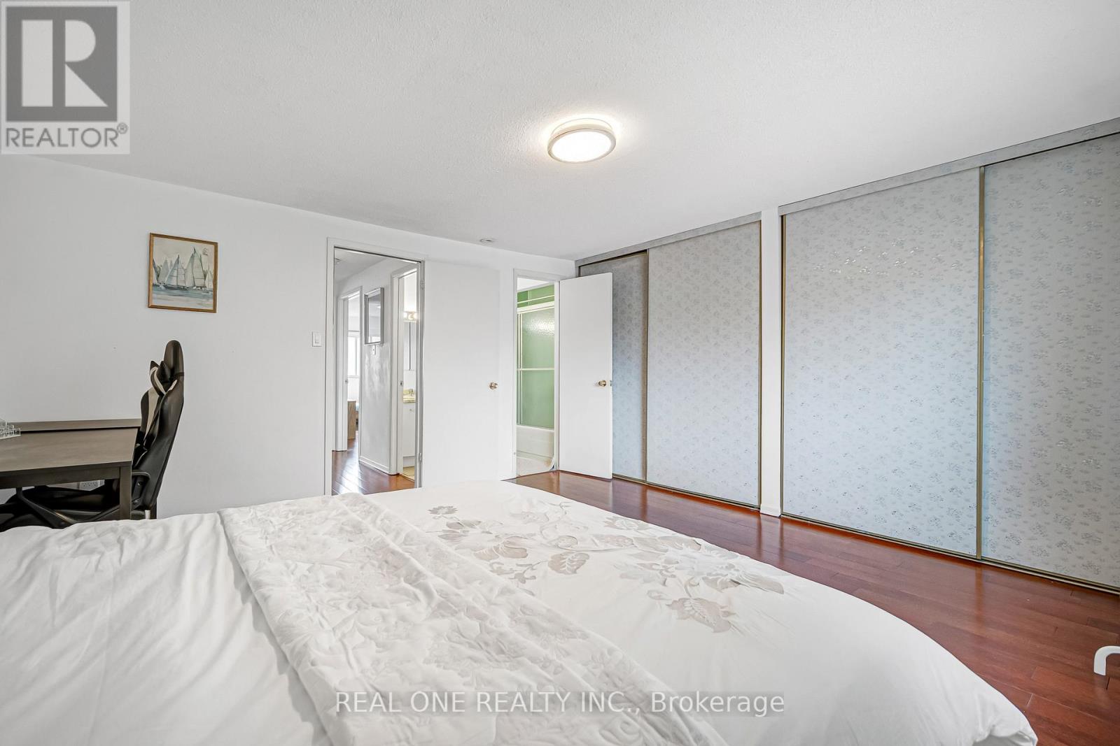 A bedroom with a large bed and a chair.