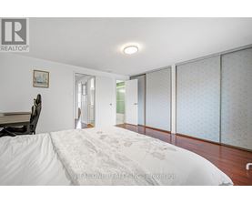 A bedroom with a large bed and a chair.