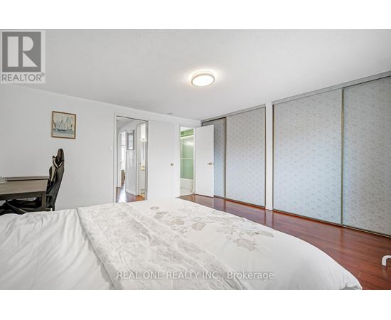A bedroom with a large bed and a chair.